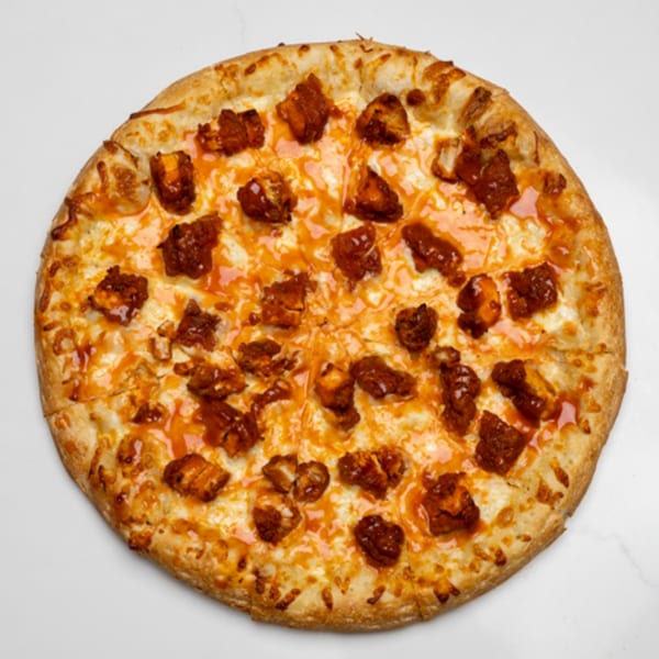 A whole Pizza Place pizza, topped with melted cheese and chunks of buffalo chicken.